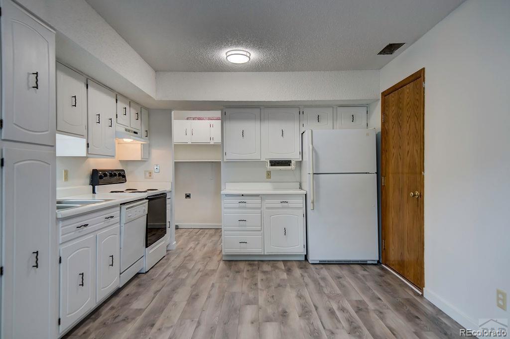 112 Scotland Road, Unit F Pueblo, CO 81001 - Photo 22 of 39 a kitchen with white cabinets and wooden floors