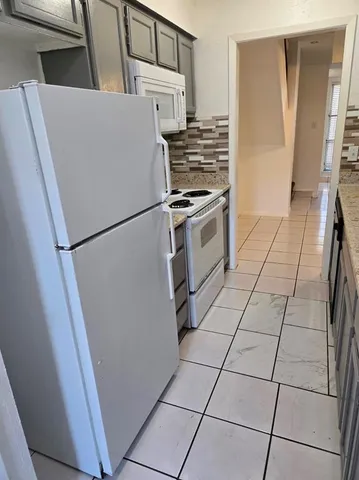 a white refrigerator freezer and a stove sitting inside of a kitchen