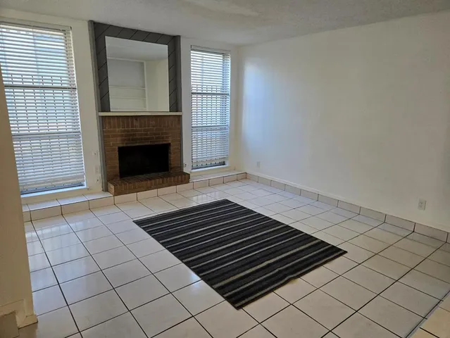 a view of an empty room with wooden floor fireplace and a window