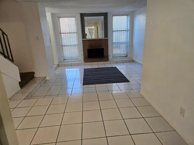 a view of an empty room with window and fireplace