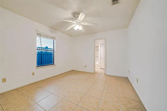 an empty room with chandelier fan and windows