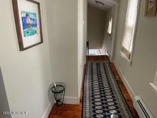 a view of a hallway with wooden floor and a bathroom