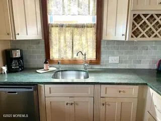a kitchen with granite countertop a sink a window and cabinets