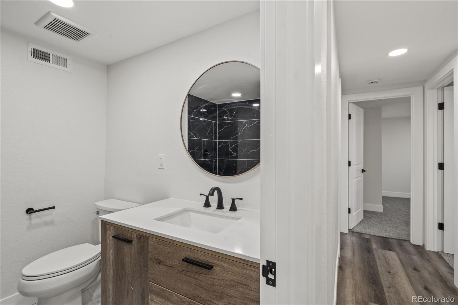 3495 Miller Street Wheat Ridge, CO 80033 - Photo 26 of 40 a bathroom with a sink a toilet and a mirror