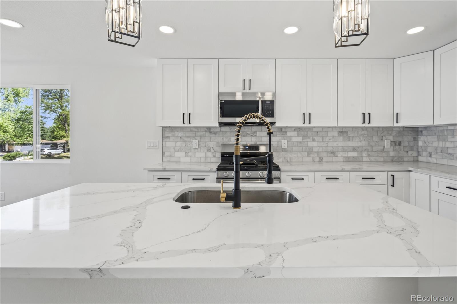 3495 Miller Street Wheat Ridge, CO 80033 - Photo 8 of 40 a kitchen with kitchen island granite countertop a sink stainless steel appliances and cabinets