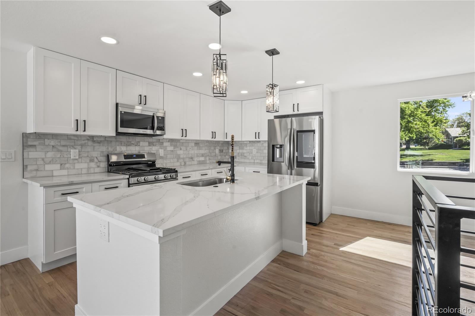 3495 Miller Street Wheat Ridge, CO 80033 - Photo 9 of 40 a large white kitchen with stainless steel appliances granite countertop a stove a sink a refrigerator and a wooden cabinets
