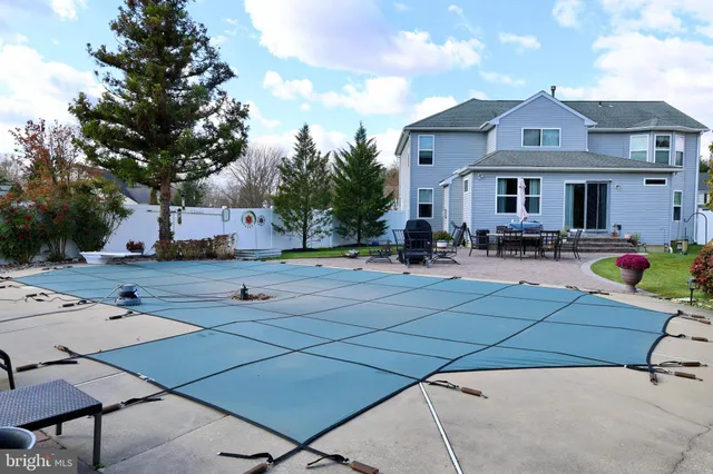 a front view of house with yard outdoor seating and trees in the background
