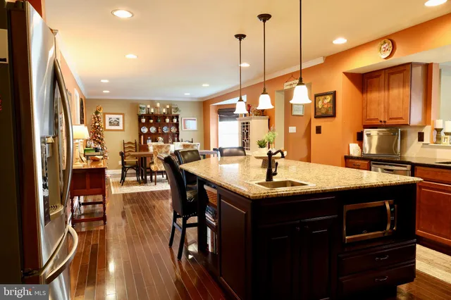 a kitchen with stainless steel appliances granite countertop a sink a stove and a wooden floors