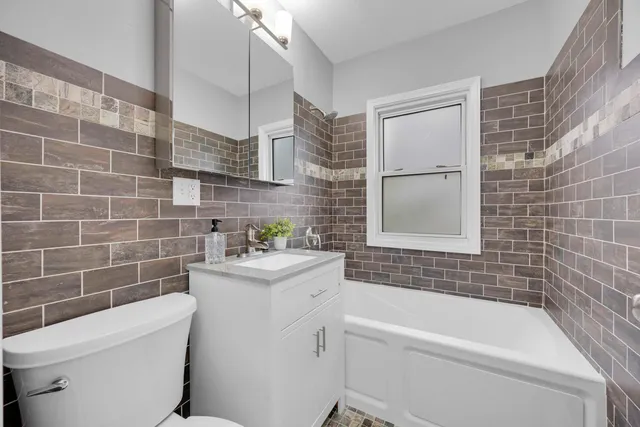 a bathroom with a sink a toilet a mirror a bathtub and shower