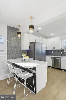 a kitchen with stainless steel appliances kitchen island granite countertop a dining table chairs and a refrigerator