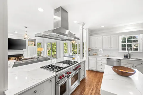 a kitchen with stainless steel appliances a stove a sink dishwasher a refrigerator and a dining table with wooden floor