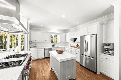 a kitchen with stainless steel appliances kitchen island granite countertop a refrigerator a sink a stove a microwave and wooden cabinets