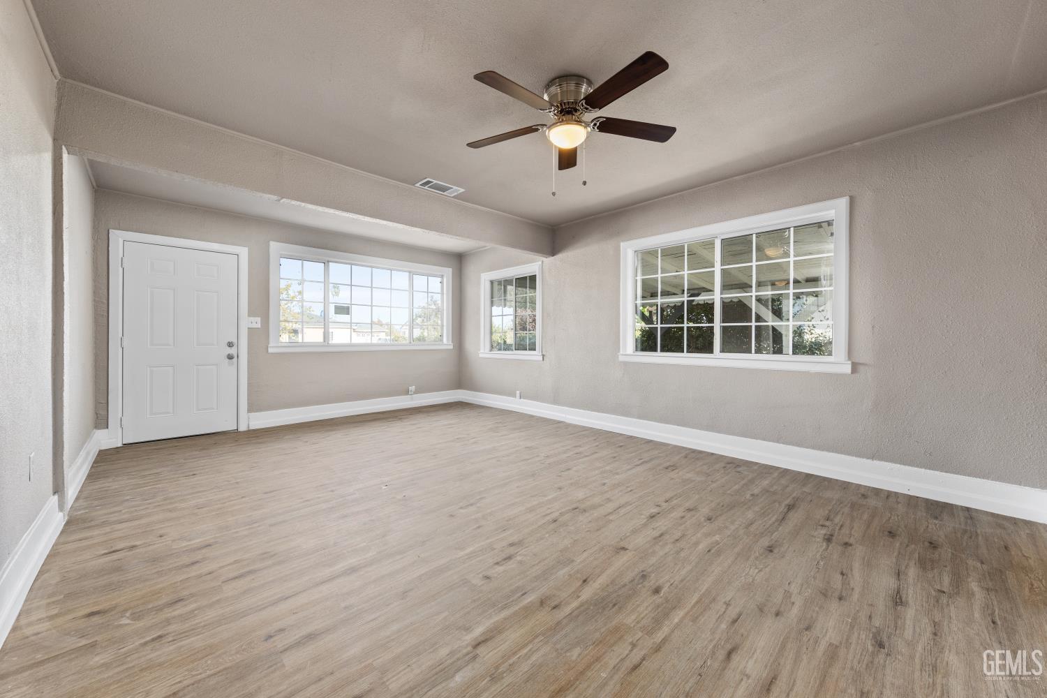 Undisclosed Address Bakersfield, CA 93305 - Photo 6 of 32 an empty room with wooden floor and windows