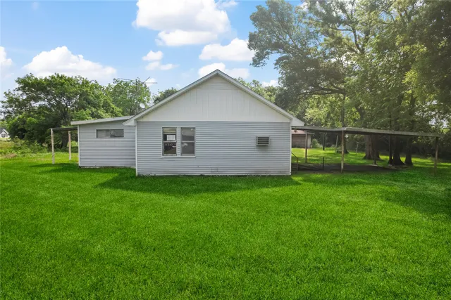 a view of a yard in front of a house with large trees