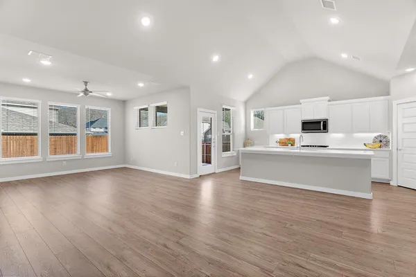 a view of a kitchen with kitchen island wooden floors and stainless steel appliances
