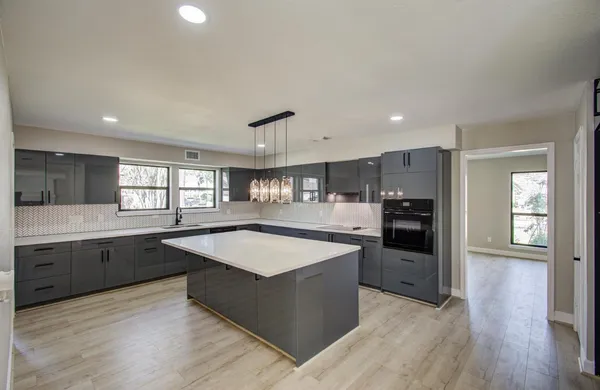 a large kitchen with stainless steel appliances granite countertop a large counter top and wooden floors