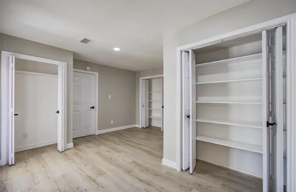 a view of an empty room with wooden floor and closet