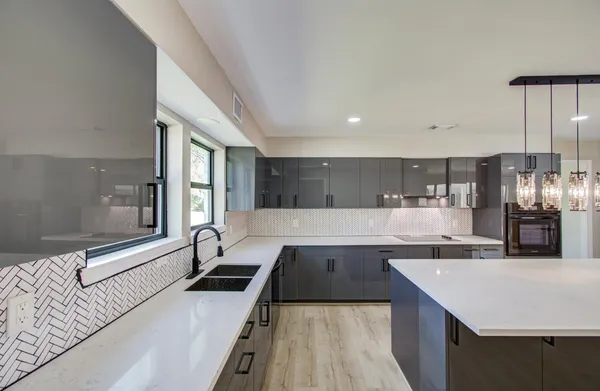 a large kitchen with a large counter top a sink stainless steel appliances and cabinets
