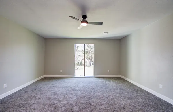 an empty room with a ceiling fan and window
