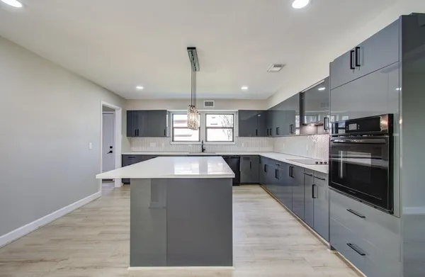 a large kitchen with stainless steel appliances kitchen island a large counter top a stove and a sink