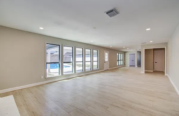 a view of an empty room with a window and wooden floor