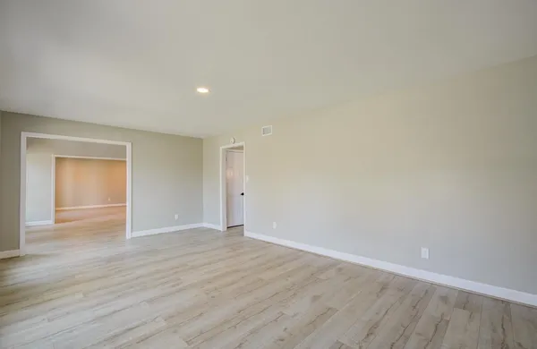 a view of an empty room with wooden floor and closet