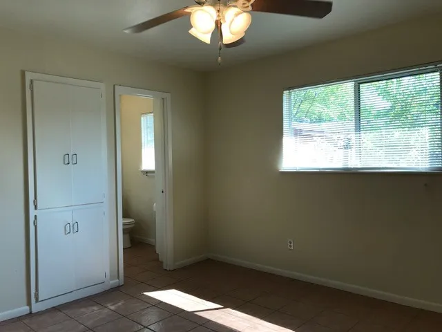 an empty room with a chandelier fan and windows