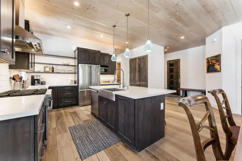 a kitchen with stainless steel appliances kitchen island granite countertop wooden cabinets a stove top oven a sink and dishwasher