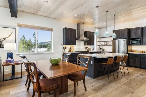 a kitchen with stainless steel appliances kitchen island granite countertop a dining table chairs and a refrigerator
