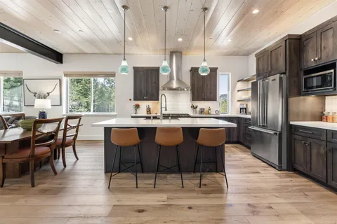 a kitchen with stainless steel appliances kitchen island granite countertop a table chairs microwave and sink