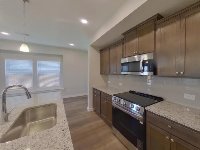a view of a kitchen with a sink and dishwasher a oven with wooden floor