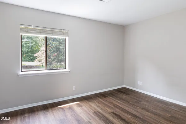 a view of an empty room with wooden floor and a bathroom