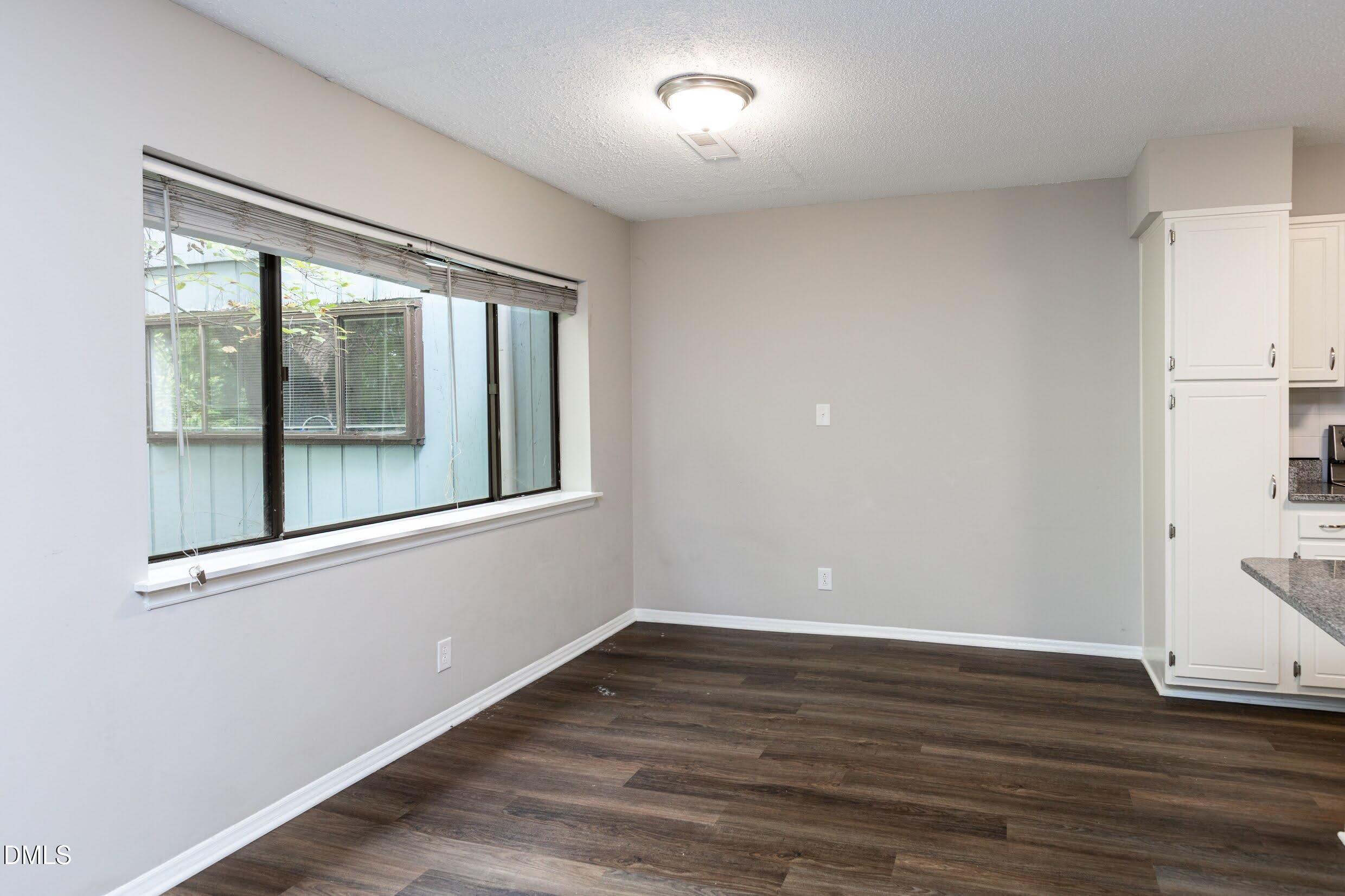 5036 Flint Ridge Place Raleigh, NC 27609 - Photo 8 of 21 a view of an empty room with wooden floor and a window