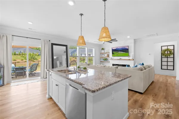 a kitchen with kitchen island granite countertop a stove and a wooden floor