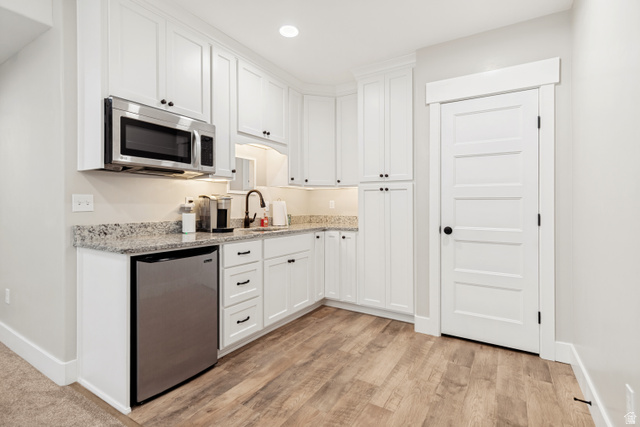 332 South 500 West Payson, UT 84651 - Photo 29 of 50 Kitchenette in basement featuring white cabinetry, a built-in microwave, a stainless-steel mini-refrigerator, light-colored speckled countertops, and wood style lvp flooring