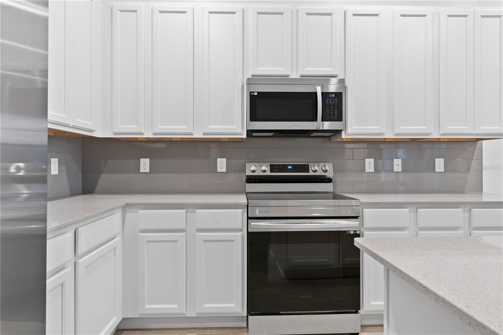 1205 Butterfly Orchid Road Davenport, FL 33837 - Photo 11 of 69 a kitchen with white cabinets and stainless steel appliances