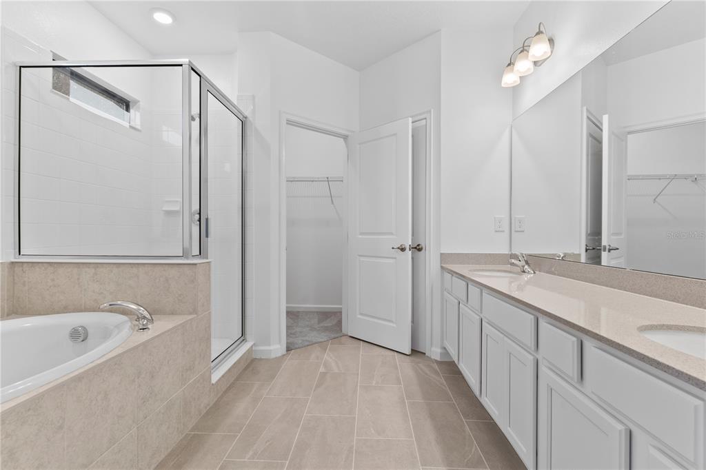 1205 Butterfly Orchid Road Davenport, FL 33837 - Photo 29 of 69 a bathroom with a tub sink and mirror