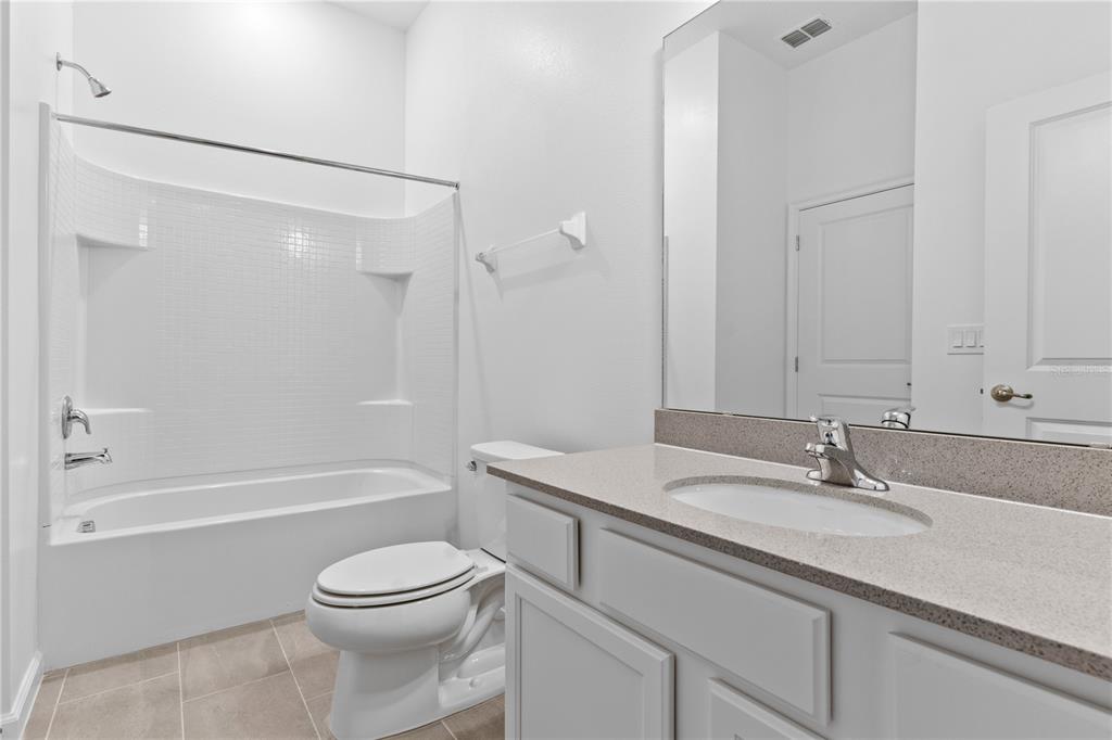 1205 Butterfly Orchid Road Davenport, FL 33837 - Photo 34 of 69 a bathroom with a granite countertop sink a toilet and shower