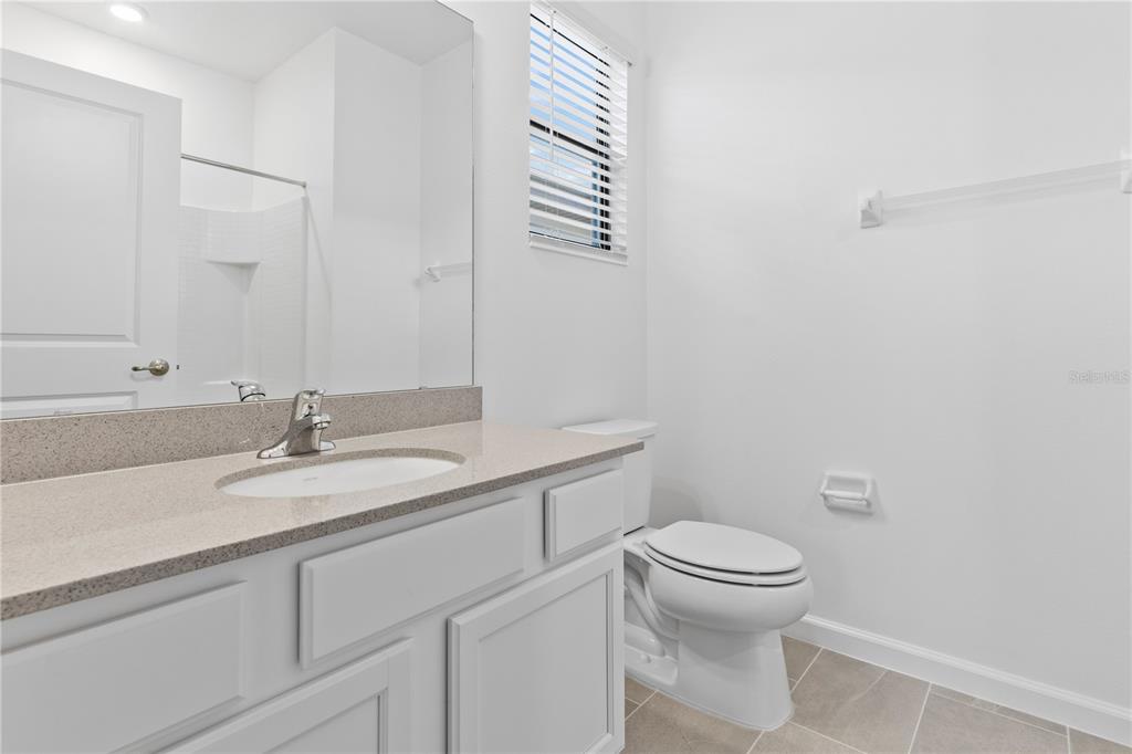 1205 Butterfly Orchid Road Davenport, FL 33837 - Photo 37 of 69 a bathroom with a granite countertop toilet sink and mirror
