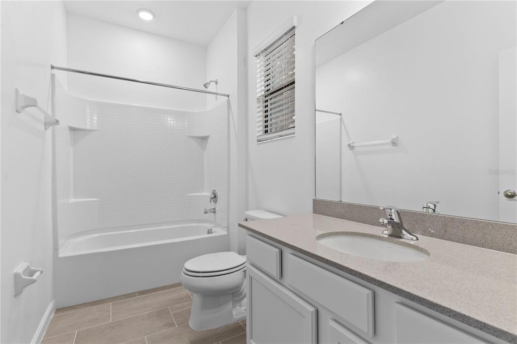 1205 Butterfly Orchid Road Davenport, FL 33837 - Photo 40 of 69 a bathroom with a granite countertop sink a toilet and shower