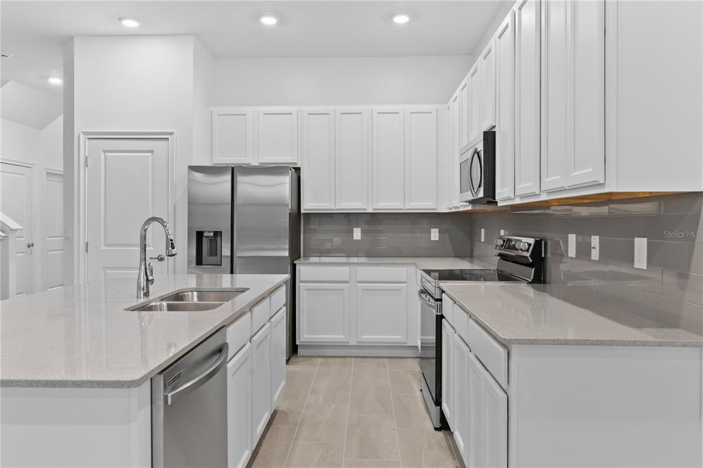 1205 Butterfly Orchid Road Davenport, FL 33837 - Photo 10 of 69 a kitchen with stainless steel appliances granite countertop a sink stove and refrigerator