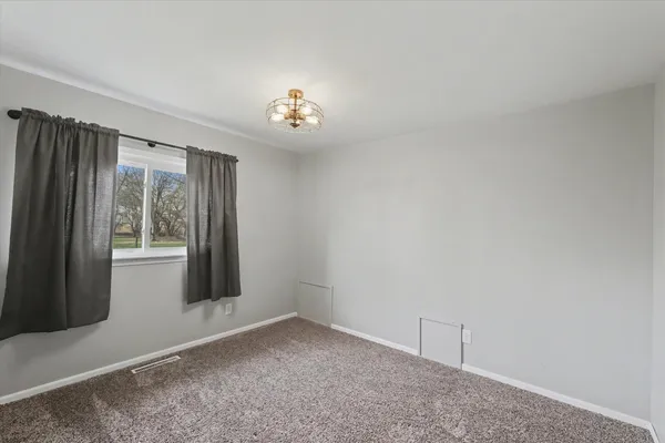 an empty room with a chandelier fan and a window