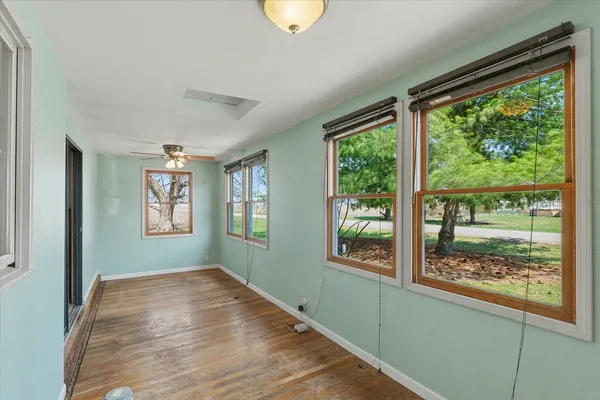 a view of an empty room with wooden floor and a window