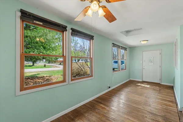 a view of empty room with wooden floor and fan