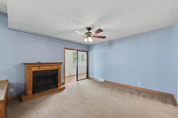 a view of an empty room with a fireplace and a ceiling fan