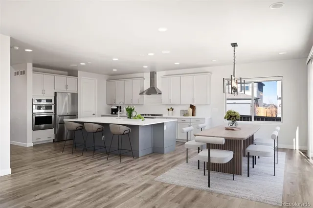 a kitchen with a dining table chairs wooden floor cabinets appliances and a center island