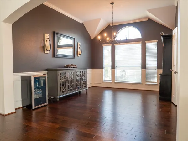 an empty room with wooden floor windows and a chandelier