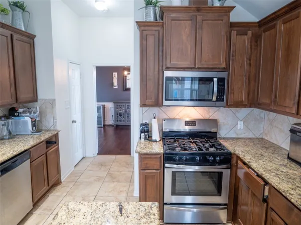 a kitchen with granite countertop a stove top oven microwave and refrigerator