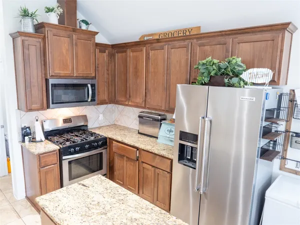 a kitchen with granite countertop a refrigerator stove and microwave