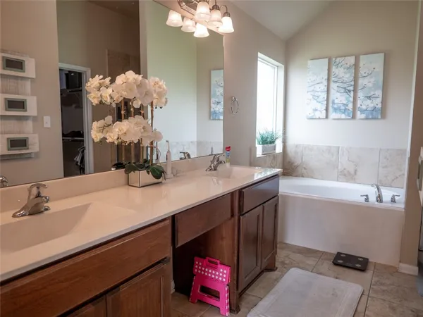 a bathroom with a double vanity sink mirror and bathtub